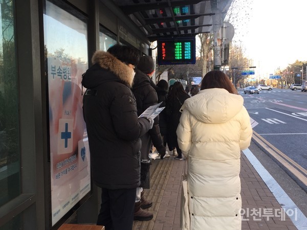 버스정류소에서 시 직원이 시내버스 노선개편 안내지를 나눠주고 있다.