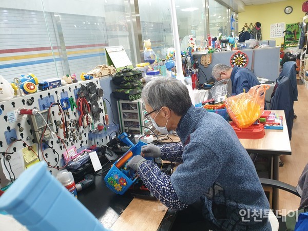  신중년 사회공헌활동 참가자가 키니스장난감병원에서 장난감을 수리하고 있다.(사진제공 일터와사람들)