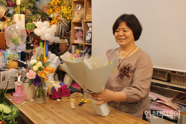 류승실 대표가 꽃다발을 만들며 행복한 미소를 짓고 있다.