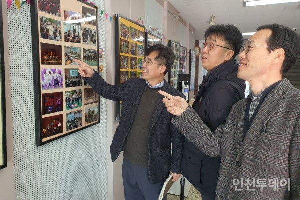 (왼쪽부터)성기신, 김영석, 고두한 교사가 선학중학교에 전시된 과거 행사 사진들을 보며 회상하고 있다.