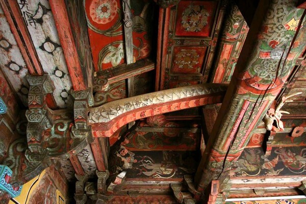 사진 한가운데 용의 몸처럼 생기고 휘어 있는 부재가 충량이다. 들보를 넘어 반대쪽 끝은 용머리로 장식했다. 사진처럼 충량은 한쪽 끝이 기둥머리에 짜이고 다른 쪽 끝은 들보 위에 걸친다. 충량은 대들보와 측벽을 잡아주어 짜임새를 튼튼하게 한다. 그래서 건물 안에 따로 기둥을 세우지 않아도 되어 내부 공간을 넓게 쓸 수 있다. 사진 출처: 국가유산청